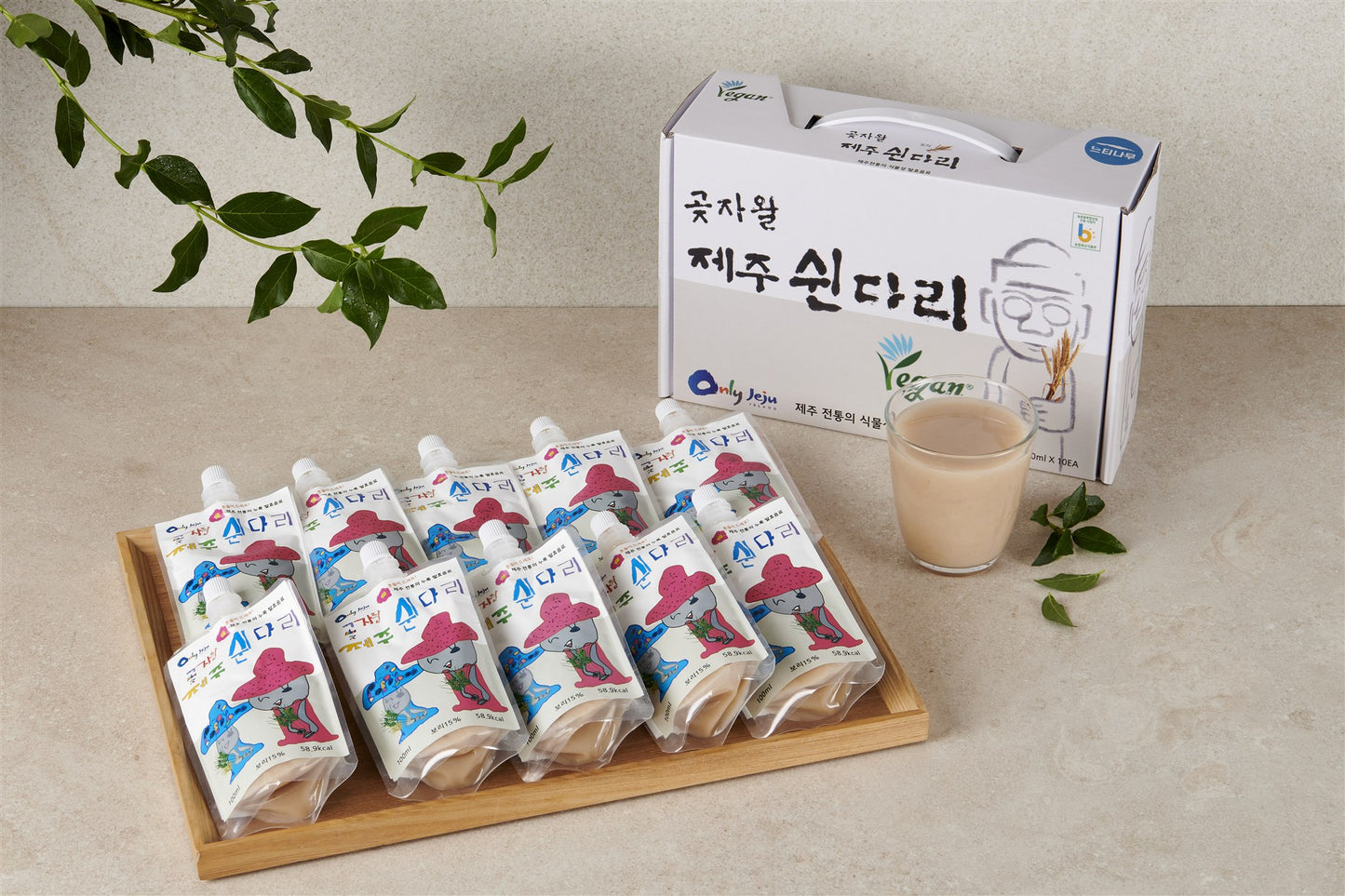 Gotjawal Jeju Swindari barley pouches in a wooden tray with gift box and a glass, studio shot